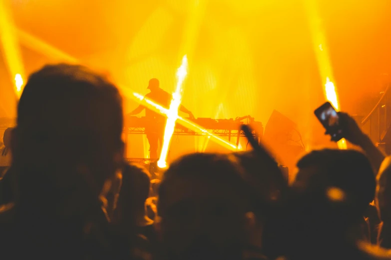 a group of people that are standing in front of a stage, pexels, synthetism, glowing orange lasers, techno concert advert, silhouette of a man, yellow lights