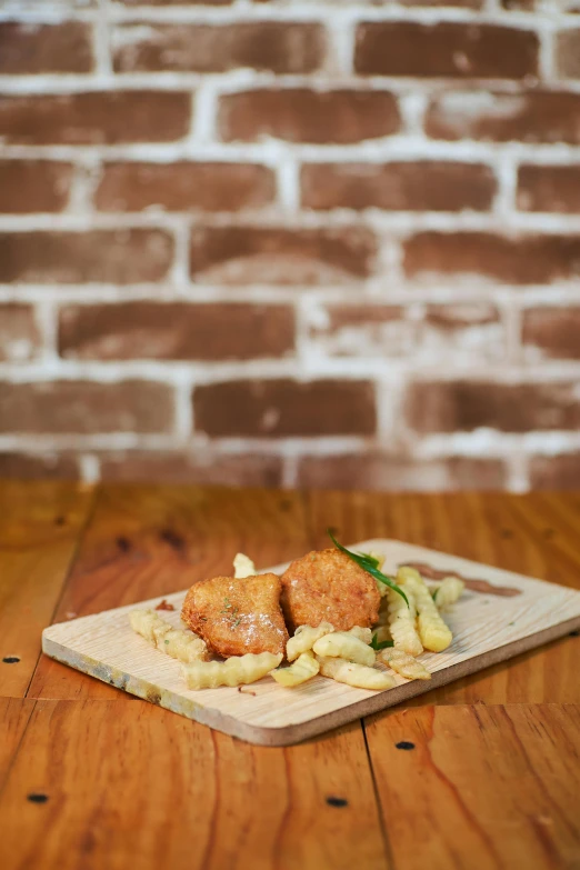 a wooden cutting board topped with food on top of a wooden table, deep fried, nugget, shot with sony alpha, square