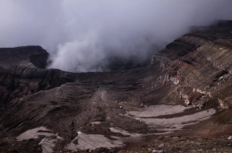 a group of people standing on top of a mountain, a picture, unsplash contest winner, sumatraism, dark smoke in distance, geological strata, crater, under a gray foggy sky