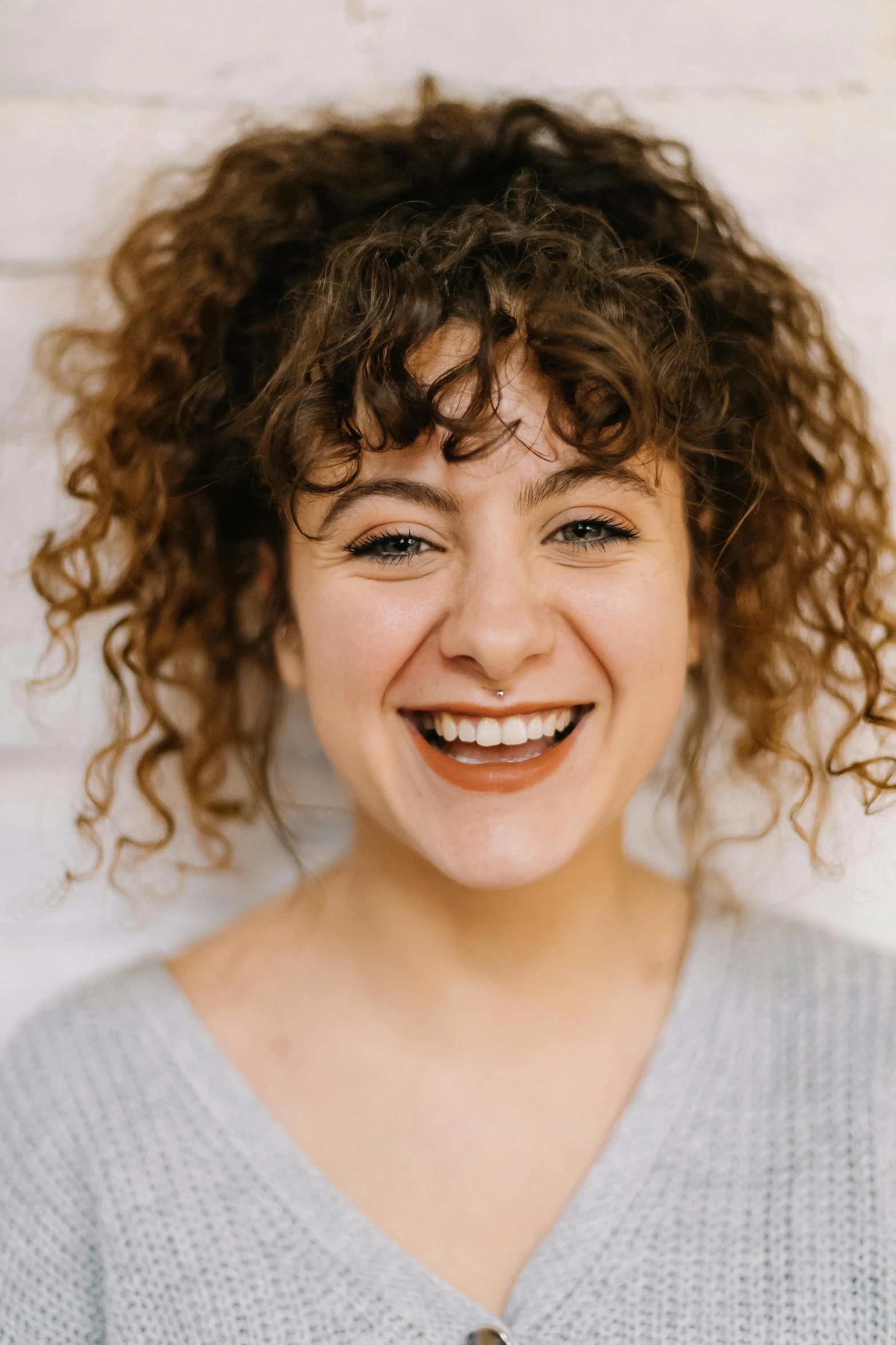 a woman with curly hair smiling at the camera, by Jessie Algie, acting headshot, rebecca sugar, on clear background, loosely cropped