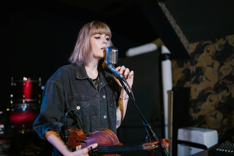 a woman singing into a microphone while holding a violin, unsplash, with a fringe, charli bowater, heath clifford, half length