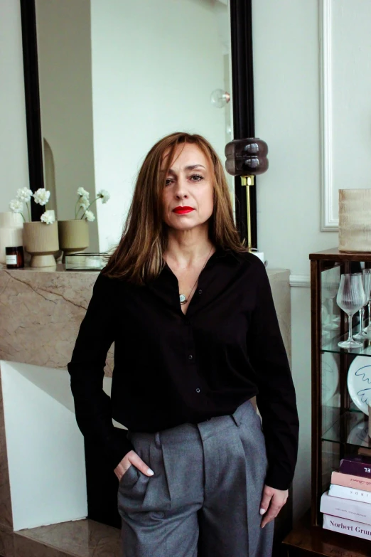 a woman standing in a living room next to a fireplace, inspired by Eva Gonzalès, instagram, wearing black business suit, francine van hove, portrait image, wearing a blouse