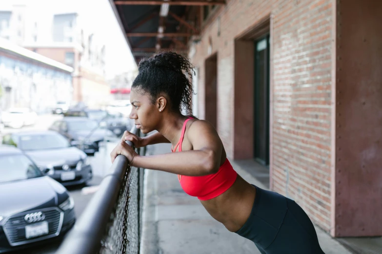 a woman leaning on the railing of a building, trending on pexels, athletic body build, photo of a black woman, multiple stories, working out
