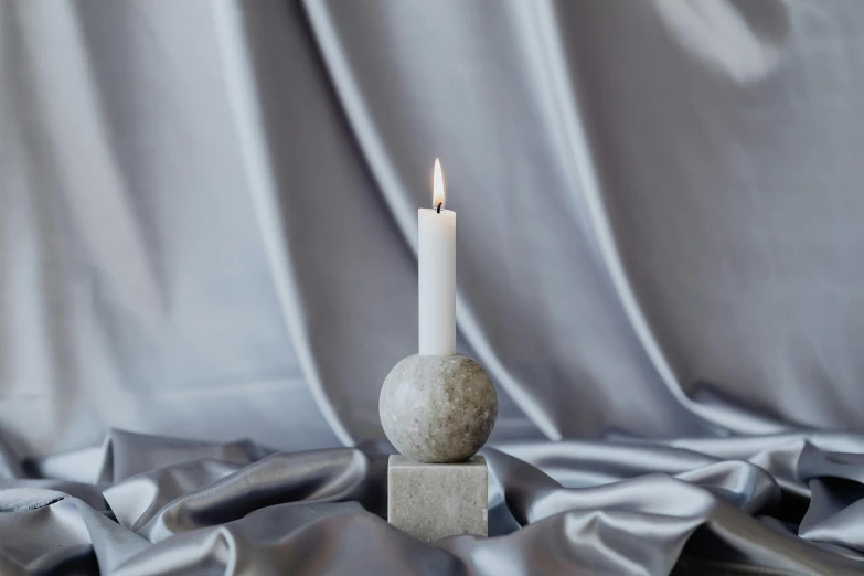 a white candle sitting on top of a stone block, a marble sculpture, inspired by Diego Giacometti, unsplash, concrete art, sphere, moonlight grey, full shot photograph, medium height