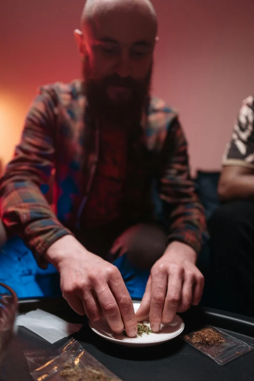 a man sitting on a couch with a plate of food, mdma, laying down with wrists together, bearded, lights on