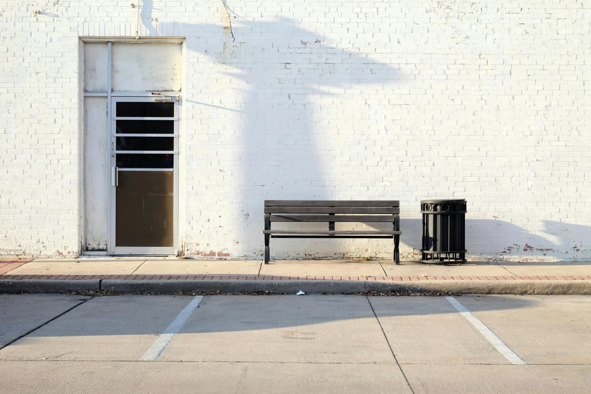 a bench and trash can in front of a white brick building, inspired by Robert Bechtle, postminimalism, heath clifford, ignant, photographic hyperrealism, street view