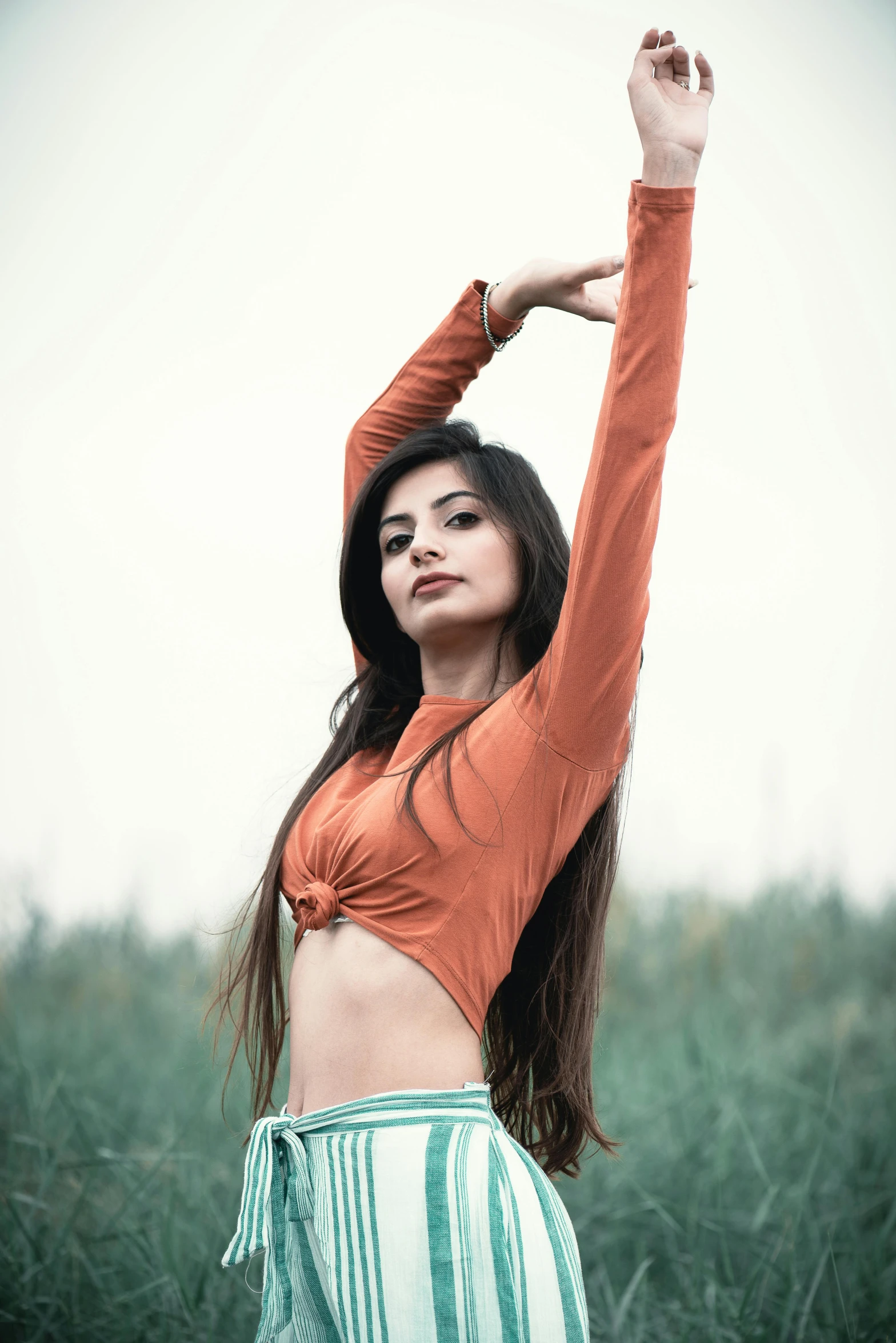 a beautiful young woman posing in a field, pexels contest winner, arabesque, wearing tight shirt, bollywood, orange tones, croptop