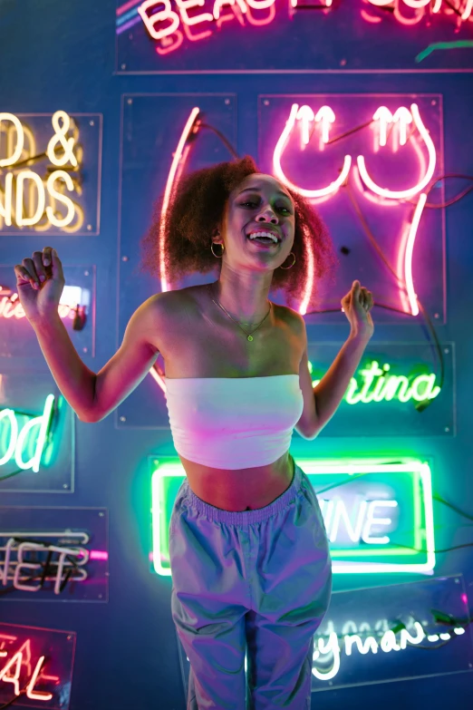 a woman standing in front of neon signs, trending on pexels, interactive art, wearing a crop top, smiling and dancing, ashteroth, pastel lighting