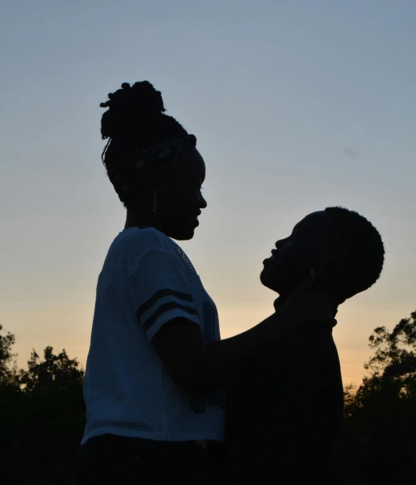 a couple of people standing next to each other, by Hannah Tompkins, pexels, happening, ( ( dark skin ) ), (golden hour), childish, profile posing