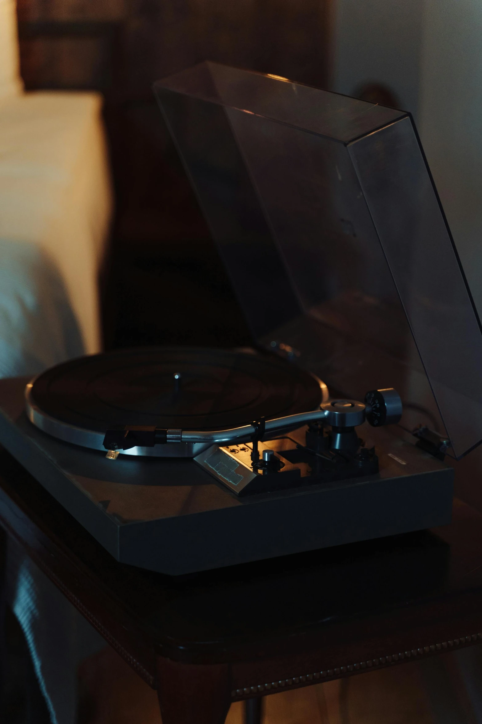 a record player sitting on top of a wooden table, during the night, looking towards the camera