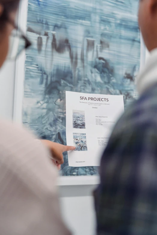 a couple of people standing in front of a poster, a picture, by Sara Saftleven, trending on unsplash, process art, on ocean, brochure, detail shot, on vellum