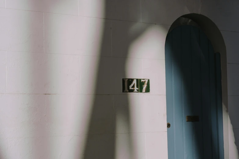 a blue door sitting next to a white wall, by Elsa Bleda, pexels contest winner, raytracing shadows, number 31 on jersey, underexposed grey, faces covered in shadows