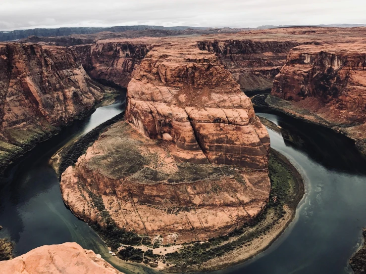 a river running through a canyon under a cloudy sky, by Tom Wänerstrand, pexels contest winner, red sandstone natural sculptures, an island floating in the air, high angle close up shot, 2000s photo