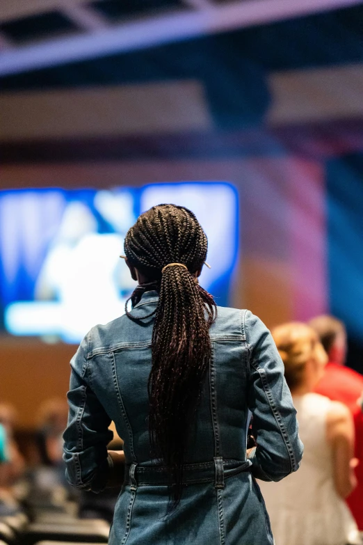 a woman standing in front of a crowd of people, from the back, wide screen, standing in a church, photo of a black woman