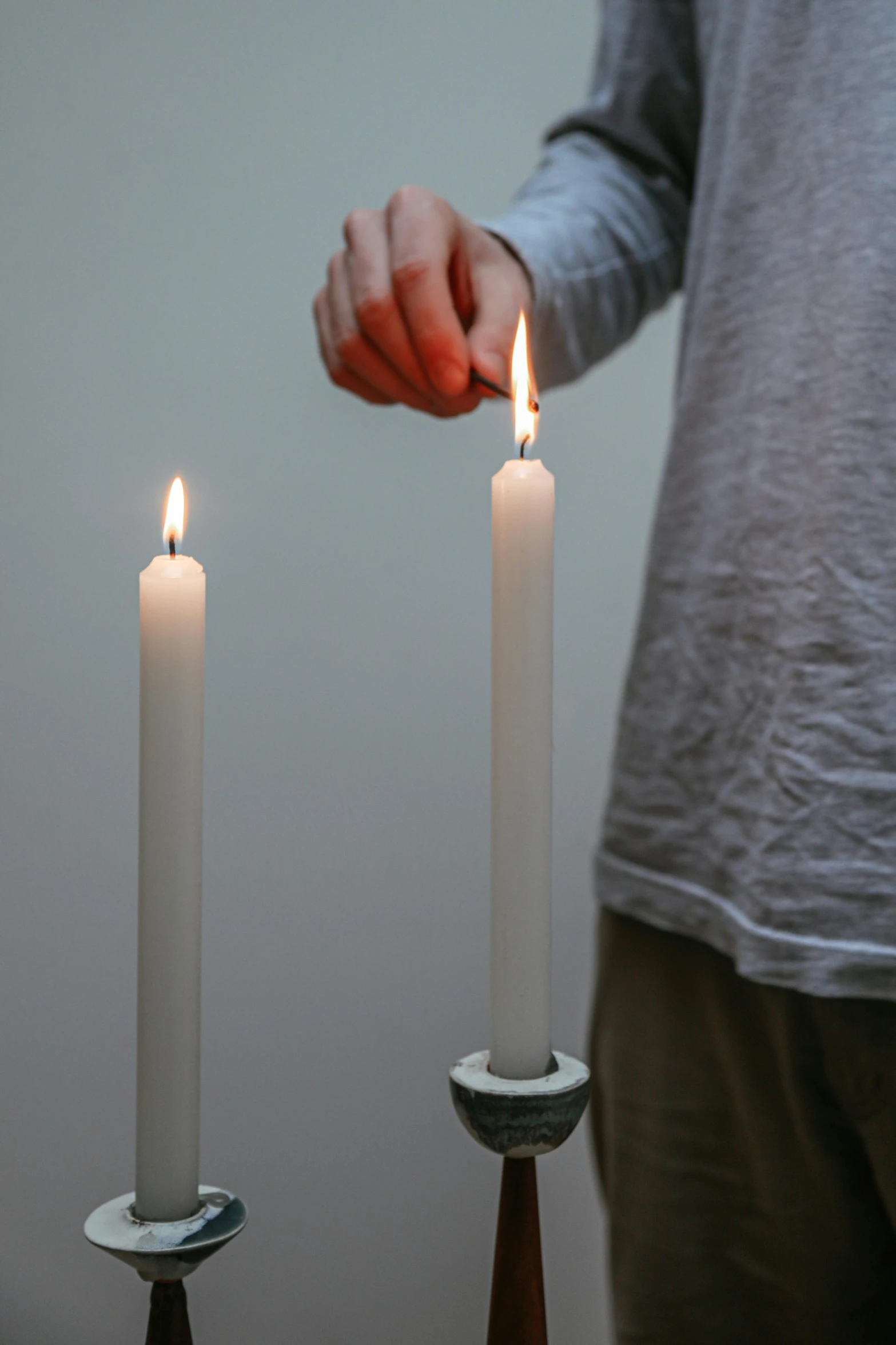 a person lighting a candle on a table, inspired by Robert Mapplethorpe, unsplash, teenage boy, holding each other, tall shot, low detail