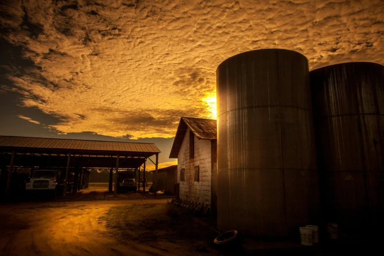 a couple of silos sitting on top of a dirt road, in the sunset, inside a farm barn, liquid gold, profile image