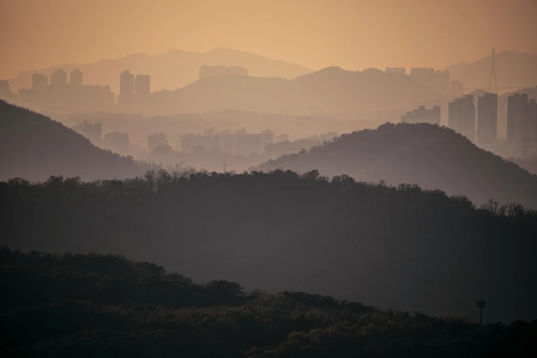 a view of a city in the distance with mountains in the foreground, inspired by Zhang Kechun, pexels contest winner, tonalism, view of forest, shenzhen, rolling hills, golden hour 8 k