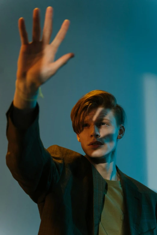 a man holding his hand up in the air, unsplash, fantastic realism, attractive androgynous humanoid, mark e smith, light show, headshot profile picture