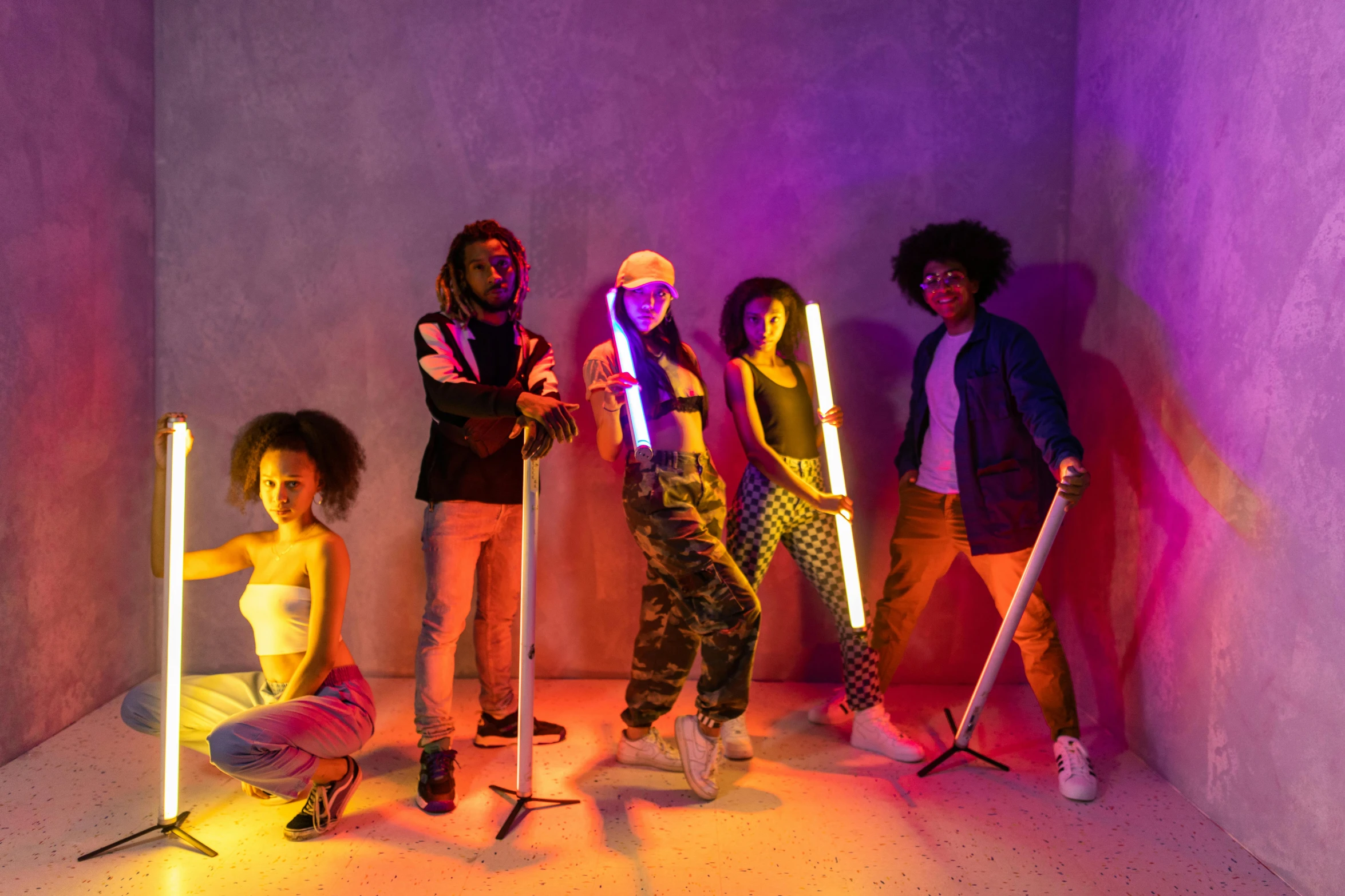 a group of people standing next to each other in a room, trending on pexels, afrofuturism, glow sticks, the scooter ( edm band, fashion color studio lighting, neon ligh