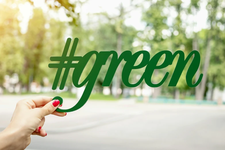 a person holding up a green hash sign, inspired by Art Green, shutterstock, environmental, hashtags, 3 d print, an elegant green