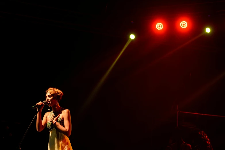 a woman standing on a stage holding a microphone, yellow lighting from right, cyarine, singer, thumbnail