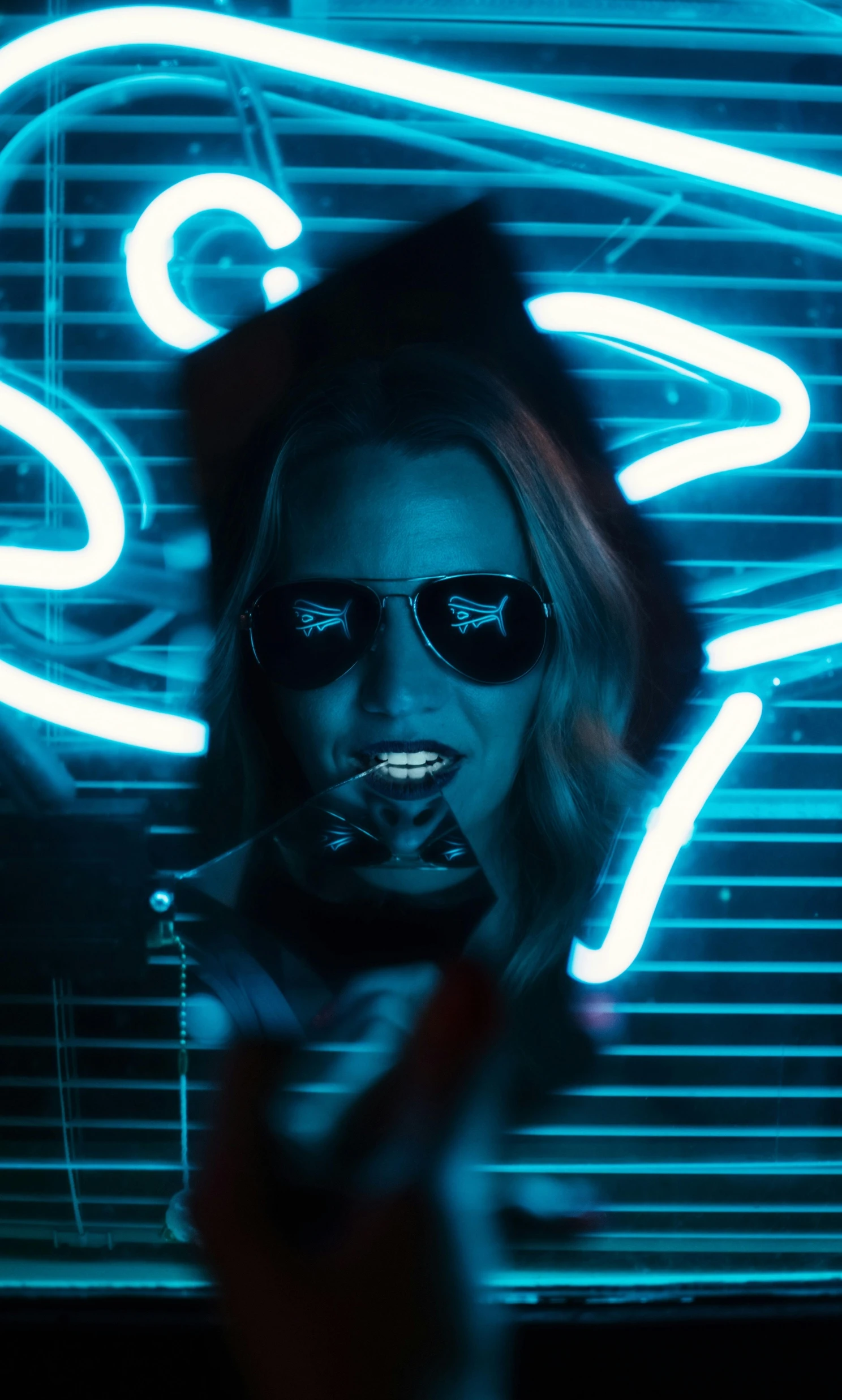 a woman standing in front of a neon sign, inspired by Elsa Bleda, reddit, blue sunglasses, film still from sin city, feral languid emma roberts, glowing mouth