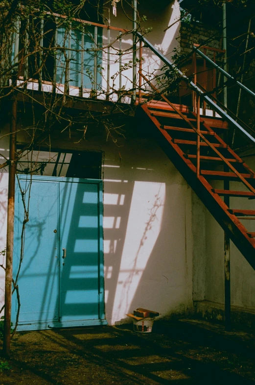 a red fire hydrant sitting next to a blue door, an album cover, inspired by Elsa Bleda, light and space, stairway, soviet yard, late afternoon sun, ladders