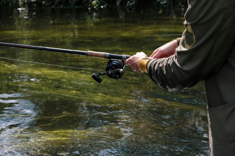 a man holding a fishing rod next to a river, by Peter Churcher, unsplash, extra detail, shot on sony a 7 iii, waterways, lightweight