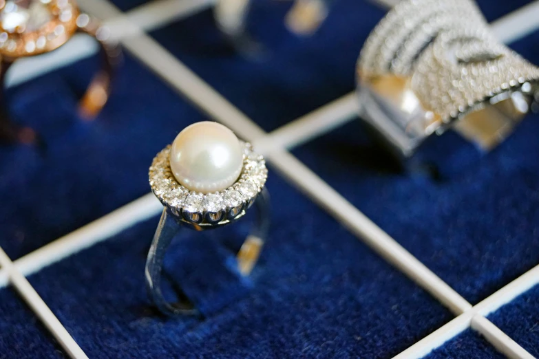 a couple of rings sitting on top of a table, pearl necklace, with sparkling gems on top, thumbnail, jewelry display