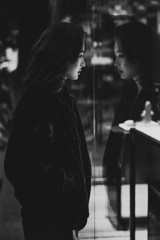 a couple of people standing next to each other, a black and white photo, tumblr, realism, admiring her own reflection, krystal, somber lighting, in a mall