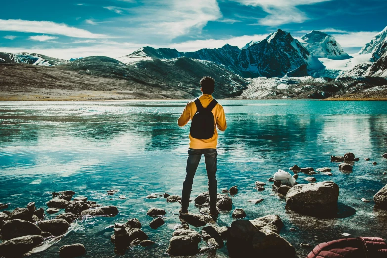 a person standing in front of a body of water, pexels contest winner, hiking clothes, avatar image, coloured photo, omar shanti himalaya tibet