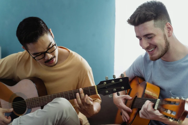 a couple of men sitting next to each other playing guitars, pexels, avatar image, student, teaching, medium head to shoulder shot