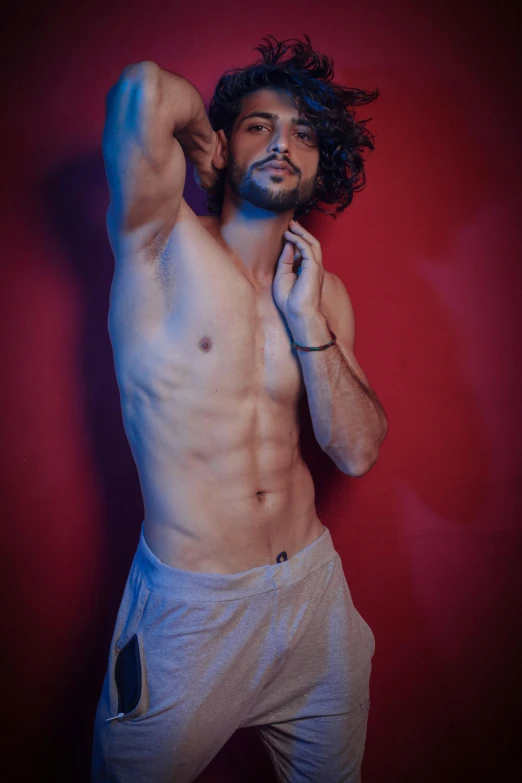 a shirtless man standing in front of a red wall, a colorized photo, by Adam Dario Keel, featured on instagram, renaissance, wavy hair spread out, by :5 sexy: 7, shot at night with studio lights, young spanish man