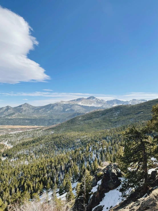 a man riding a snowboard down a snow covered slope, overlooking a vast serene forest, hiking in rocky mountain, obsidian towers in the distance, photo on iphone