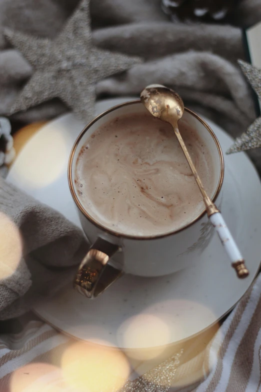 a cup of coffee sitting on top of a white plate, spoon placed, ivory and copper, thumbnail, icy