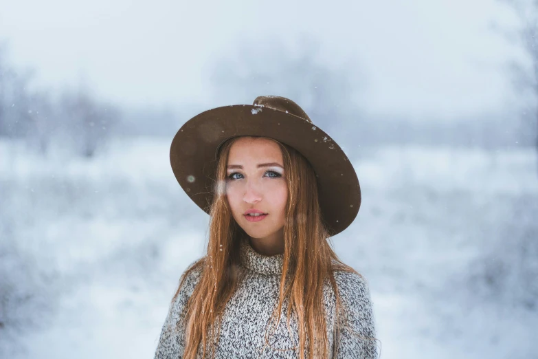 a woman wearing a hat standing in the snow, a portrait, pexels contest winner, avatar image, girl with brown hair, background image, white sky