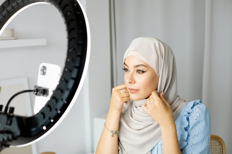 a woman in a hijab sitting in front of a camera, infinity mirror, ring light, official product photo, realistic »