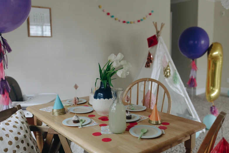 a table set for a birthday party with balloons, by Jessie Algie, pexels contest winner, teepee, strange ingredients on the table, very hazy, kitchen table