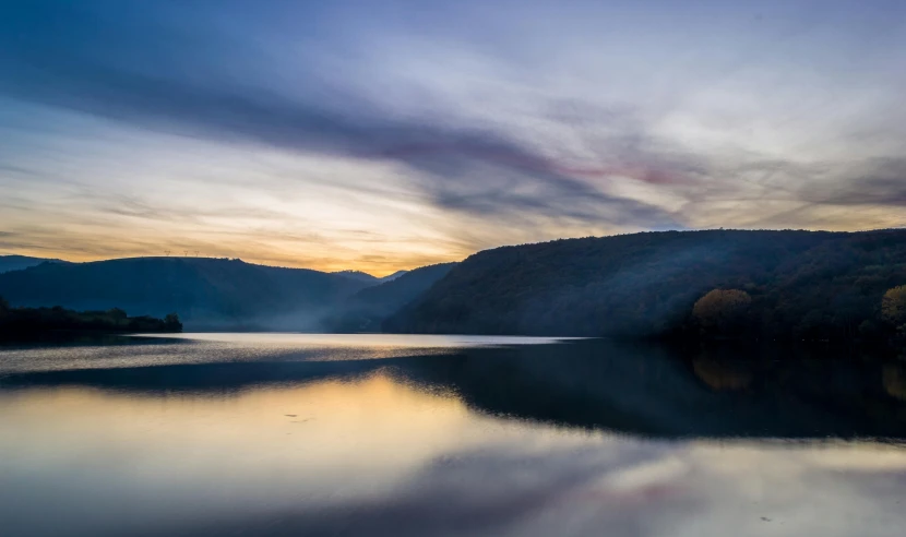 a large body of water with mountains in the background, a photo, pexels contest winner, hudson river school, sunrise colors, william penn state forest, grey, multiple stories