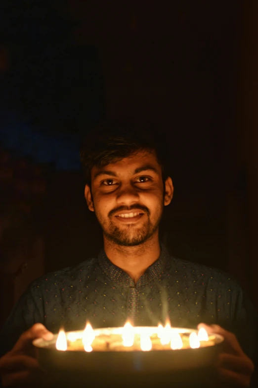 a man holding a cake with lit candles, by Max Dauthendey, pexels contest winner, ((portrait)), 2 2 years old, smiling, ismail