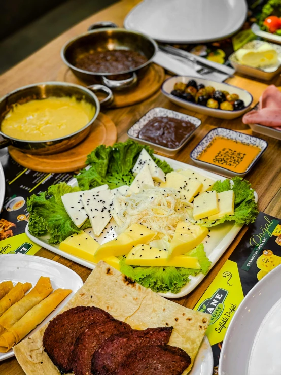 a wooden table topped with plates of food, a picture, yellow and black, thumbnail, cheesy, mekka