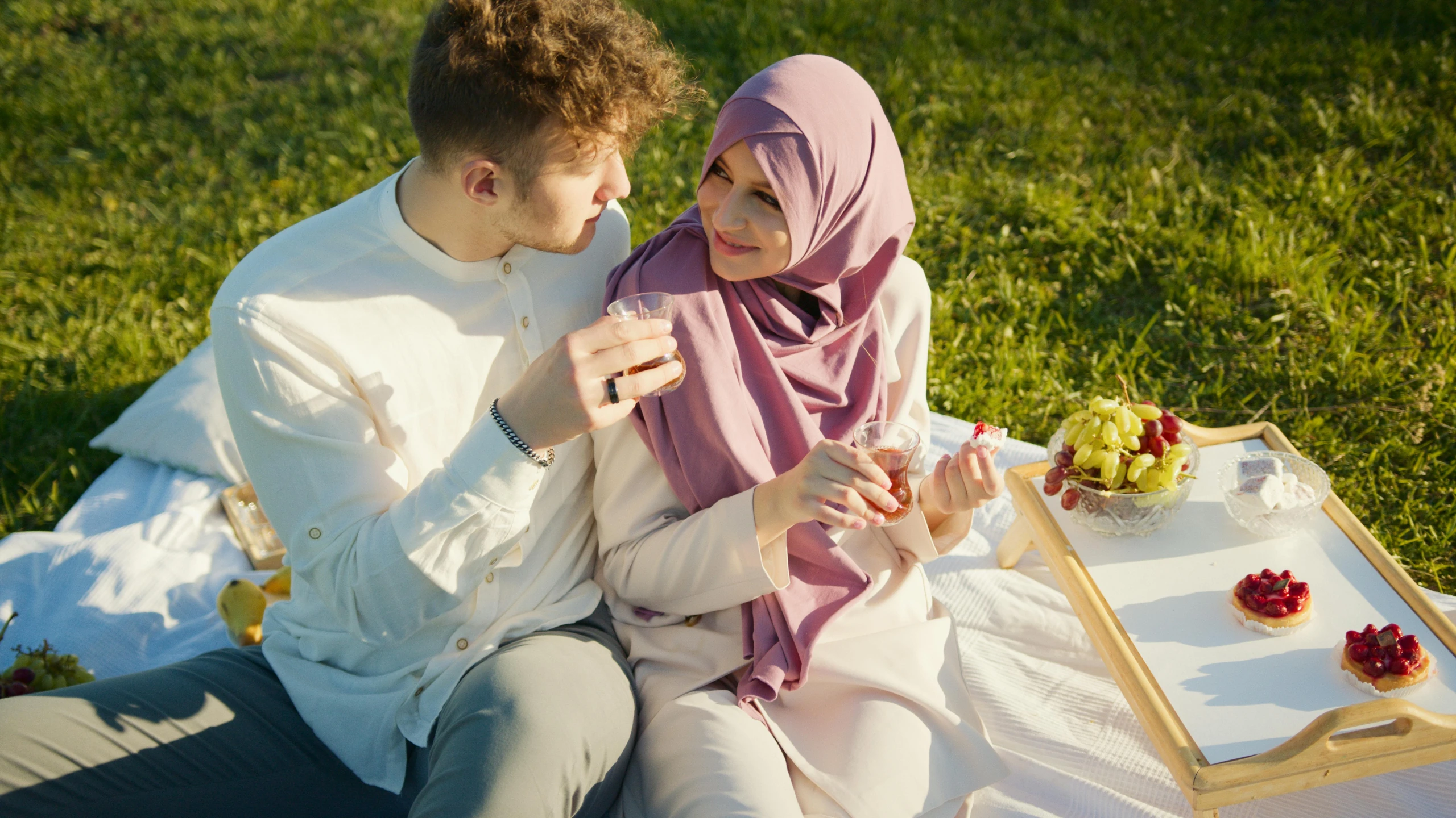 a man and a woman sitting next to each other on a blanket, a picture, shutterstock, hurufiyya, white hijab, wine, 15081959 21121991 01012000 4k, square