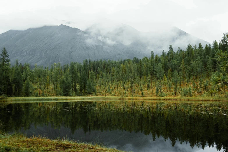 a lake with a mountain in the background, boreal forest, grey skies, russian and japanese mix, fan favorite