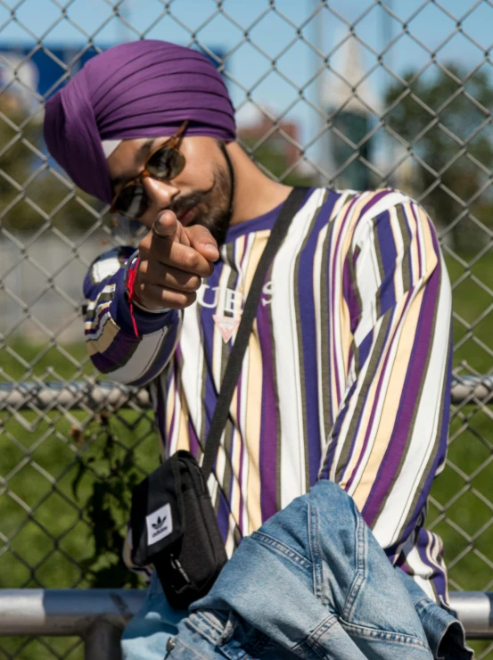 a man in a purple turban leaning against a fence, inspired by Manjit Bawa, trending on pexels, hip hop style, striped, ((purple)), various posed
