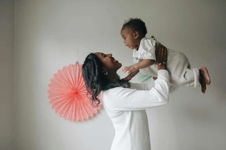 a woman holding a baby in her arms, a photo, by Arabella Rankin, pexels contest winner, wearing lab coat and a blouse, varying ethnicities, fan favorite, thumbnail