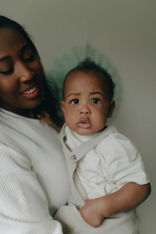 a woman holding a baby in her arms, by Arabella Rankin, pexels contest winner, portrait of ororo munroe, boy with neutral face, 1 2 9 7, low quality photo