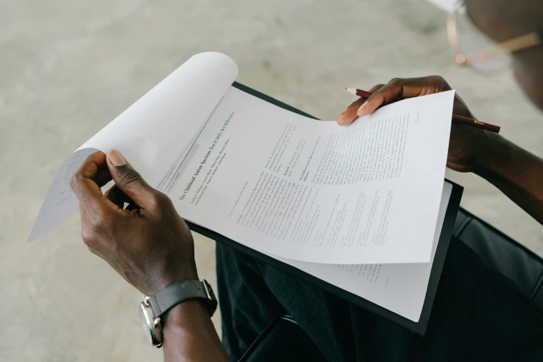 a man sitting down reading a piece of paper, by Carey Morris, pexels contest winner, on white paper, background image, riyahd cassiem, textbook pages