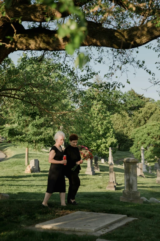 a couple of people that are standing in the grass, in a graveyard