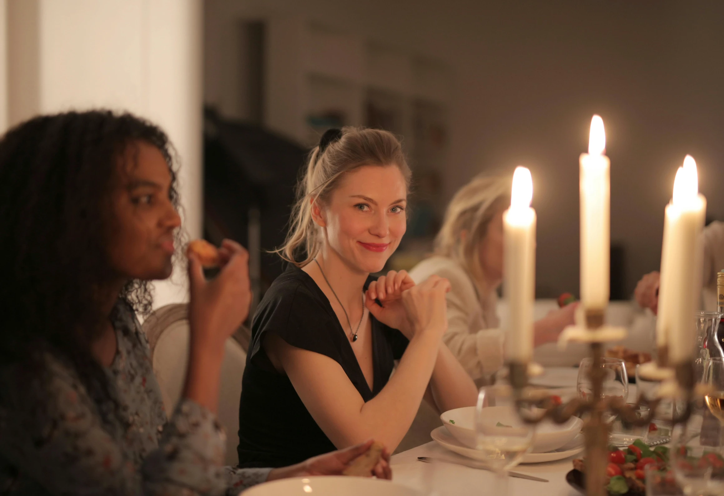 a group of women sitting around a dinner table, candle lit, nina tryggvadottir, profile image, person in foreground