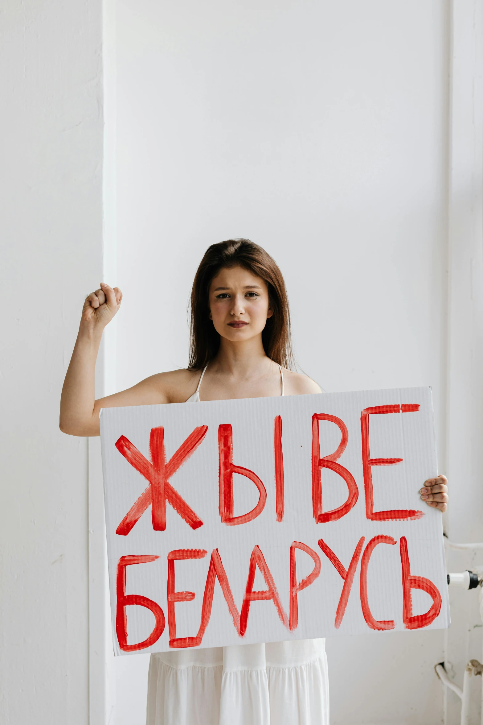 a woman in a white dress holding a sign, a poster, by Alexander Fedosav, pexels, feminist art, president of belorussia, no shirt, teenage, square